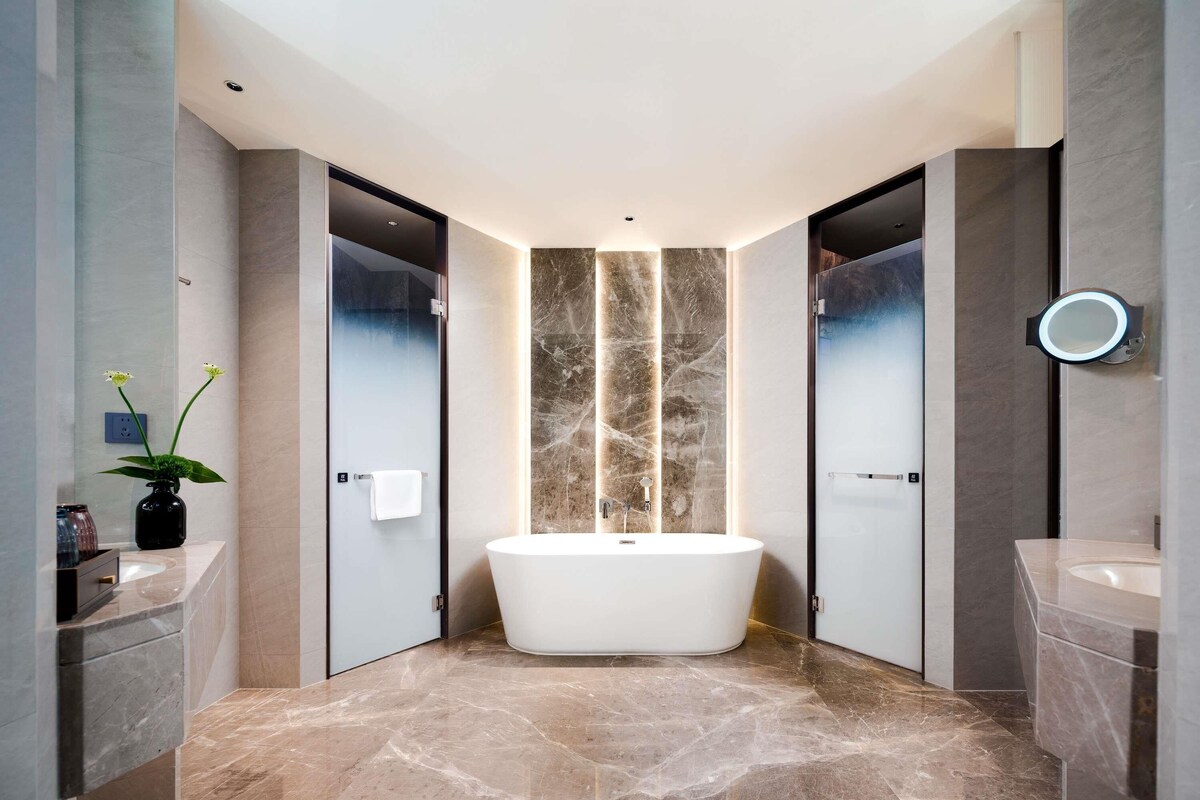 Ein modernes Badezimmer mit einer freistehenden Badewanne, zwei Waschbecken und einem großen Spiegel.