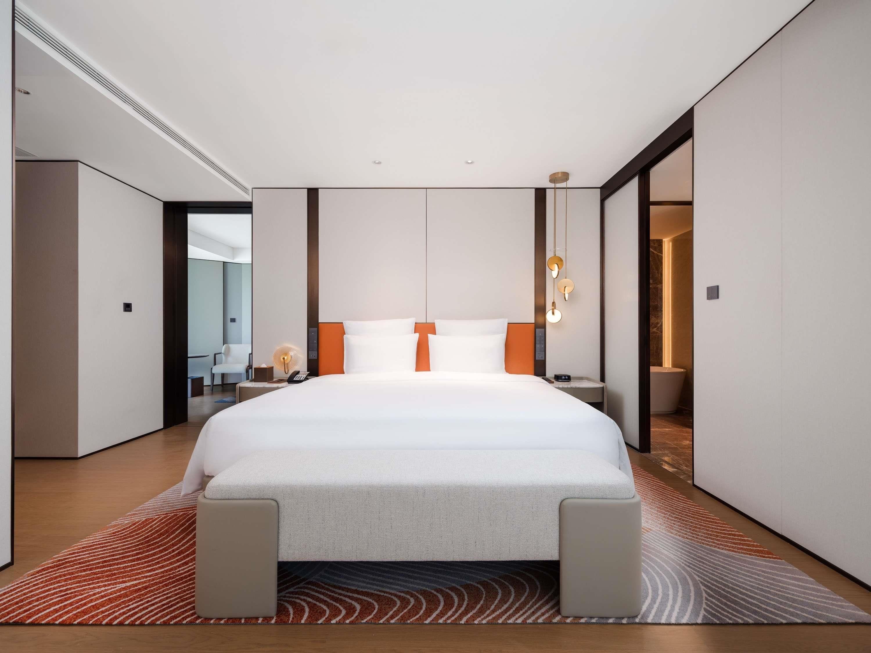 Ein modernes Hotelzimmer mit einem großen Bett, einem Schreibtisch und einem Sessel.