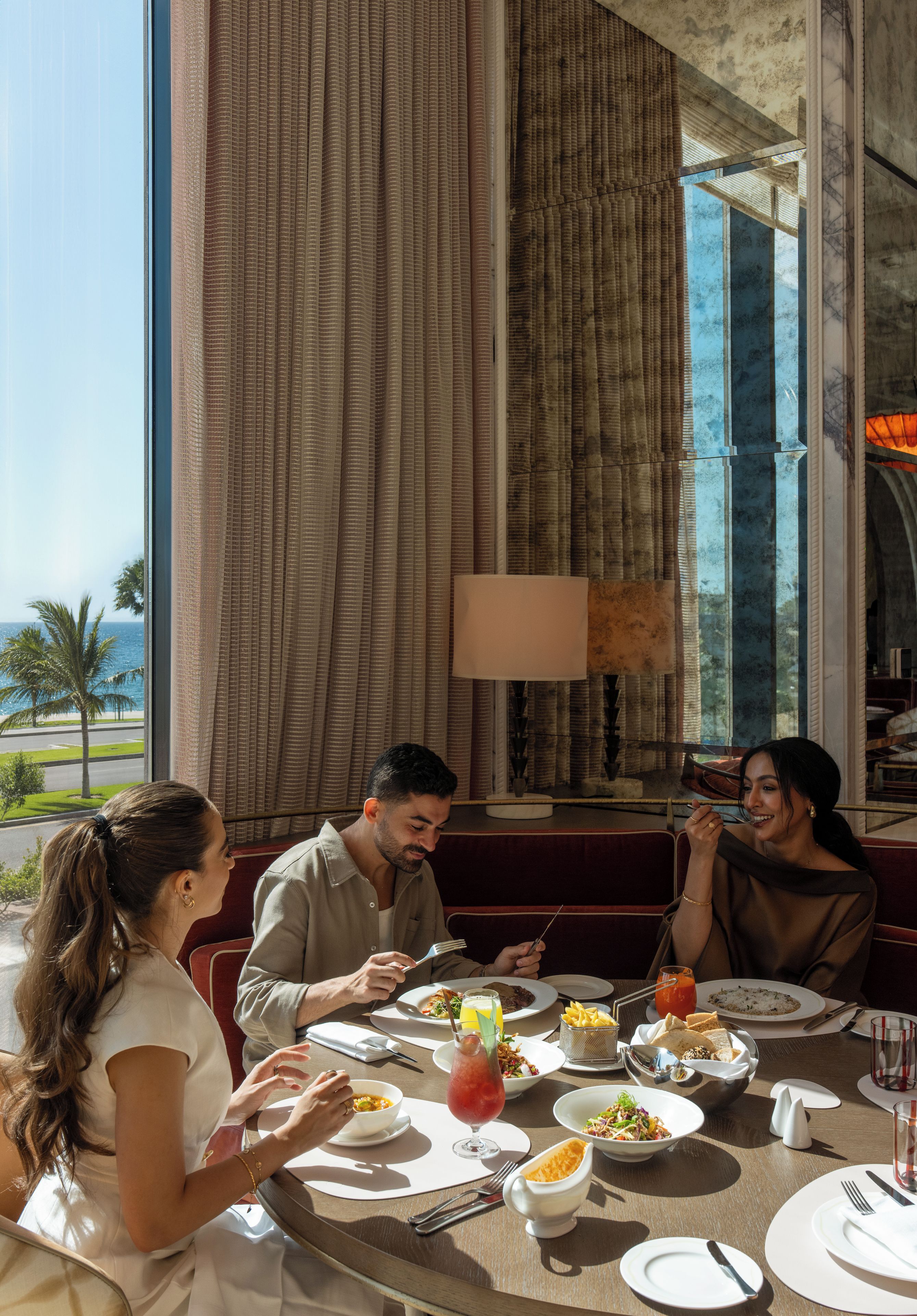A dining area with a table set for four people, a view of the outdoors, and a large window with curtains.