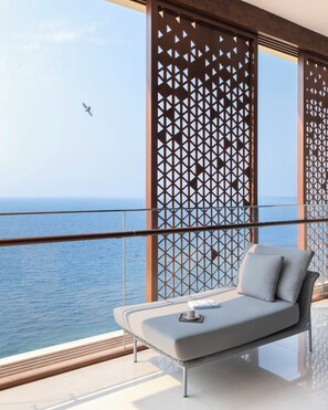 A balcony with a view of the sea, a cushioned seating area, and a decorative wooden partition. - Raffles Jeddah (Jeddah)