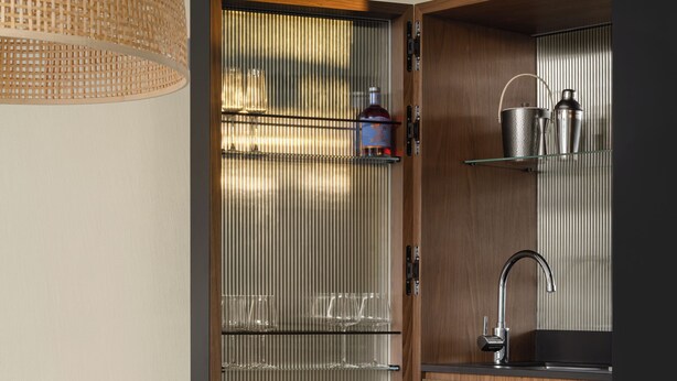 Una cucina moderna con un pensile in legno, un lavello in acciaio inossidabile e un lampadario.