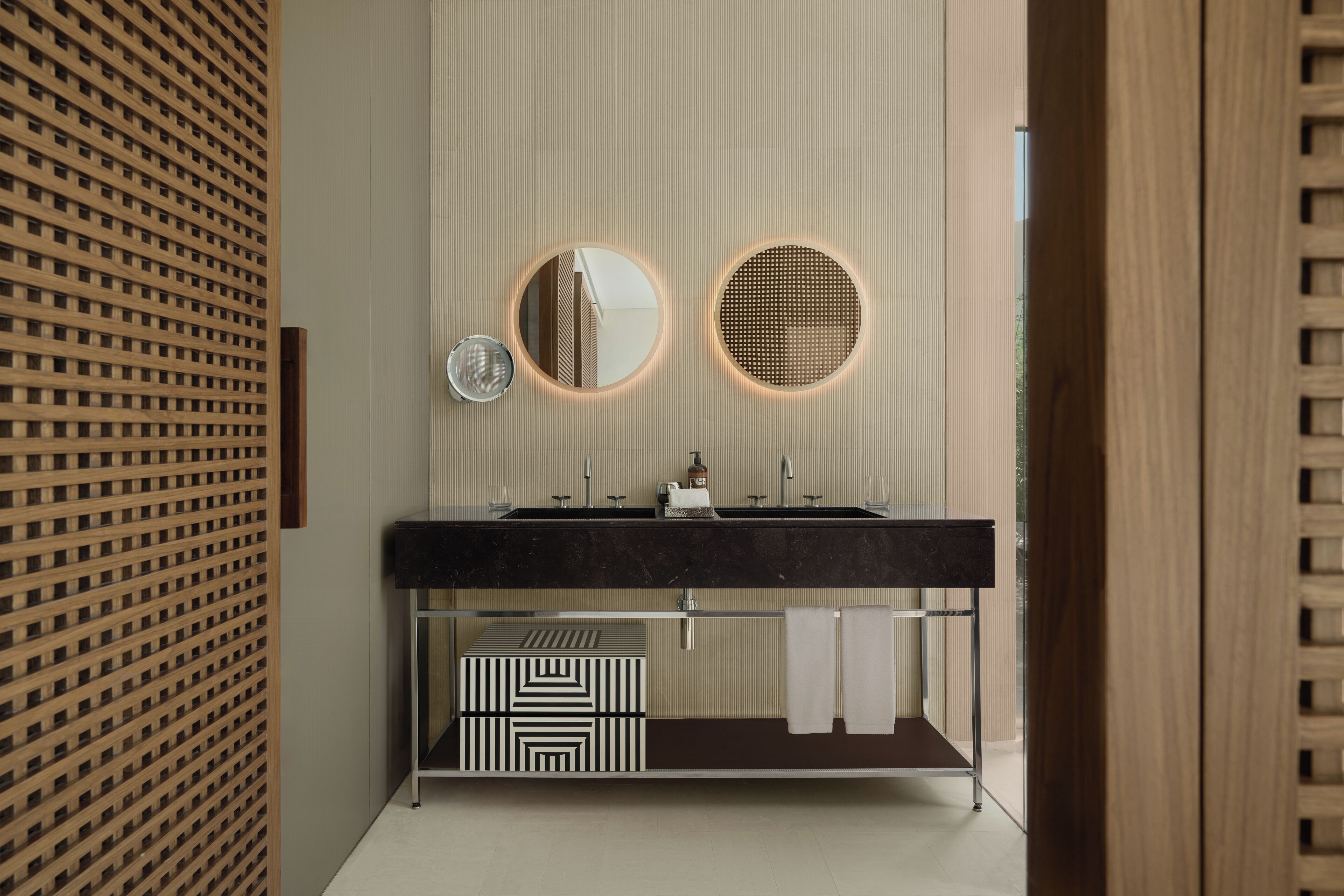 A modern bathroom with a wooden lattice wall, a black vanity with a mirror, and a patterned box.