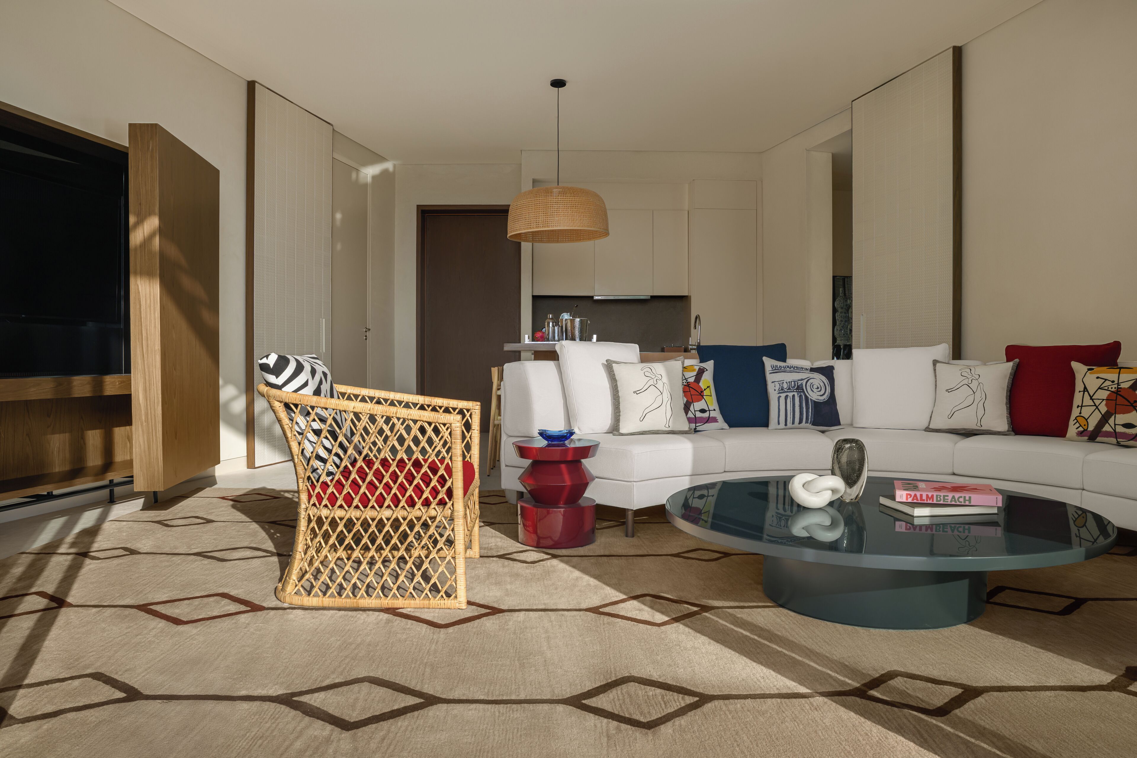 A modern living room with a sofa, a glass coffee table, and a wicker chair.