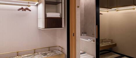 A modern bedroom with a bed, a built-in wardrobe, and a bathroom visible through an open door.