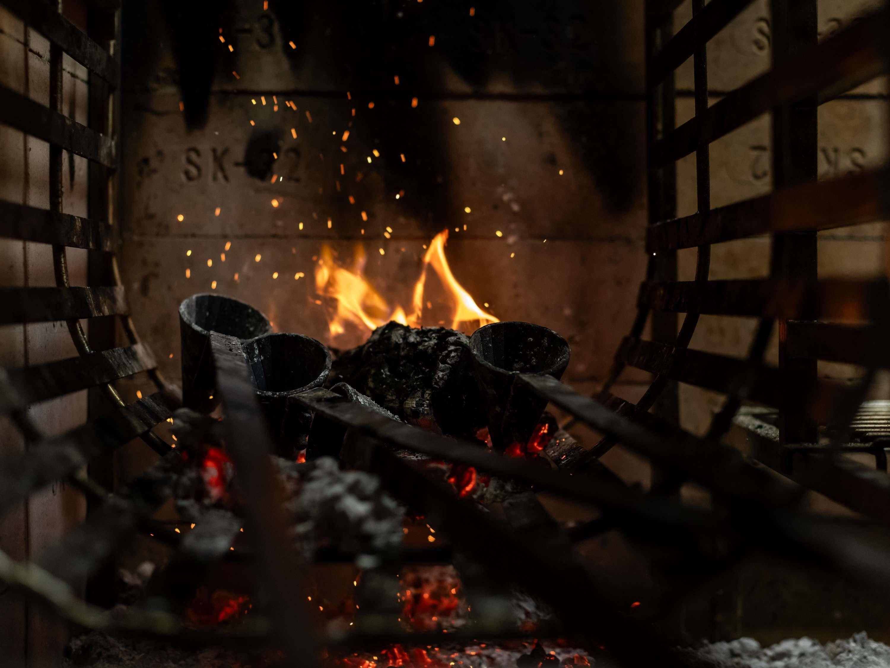 A fireplace with logs and embers, surrounded by a metal grate.