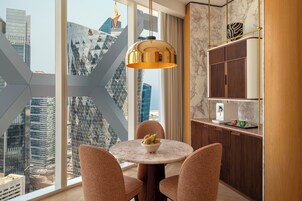 Un'area pranzo moderna con un tavolo rotondo, sedie e vista sulla città attraverso ampie finestre.