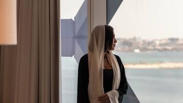 A room with a large window, a chair, and a person standing by the window.