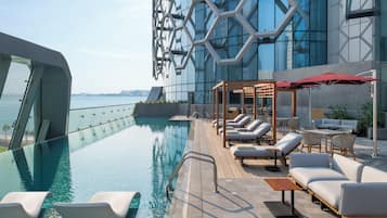 Una piscina al aire libre, sombrillas, sillones reclinables de piscina