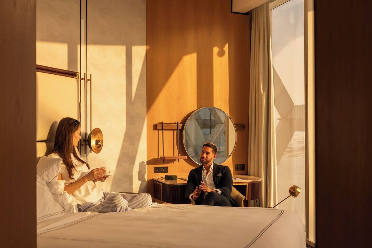 Una habitación de hotel moderna con una cama, un espejo redondo y una mesita.