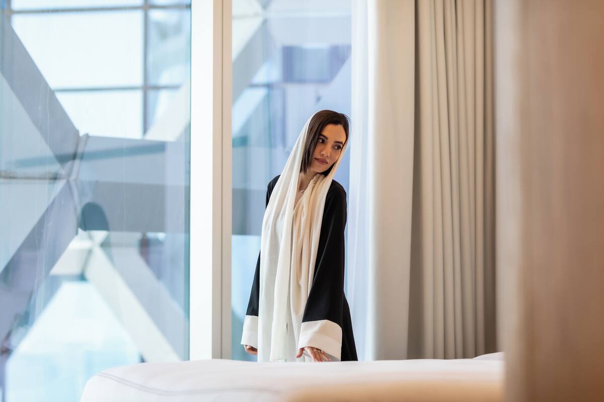 Una habitación de hotel moderna con un ventanal grande, una cama y una cortina.
