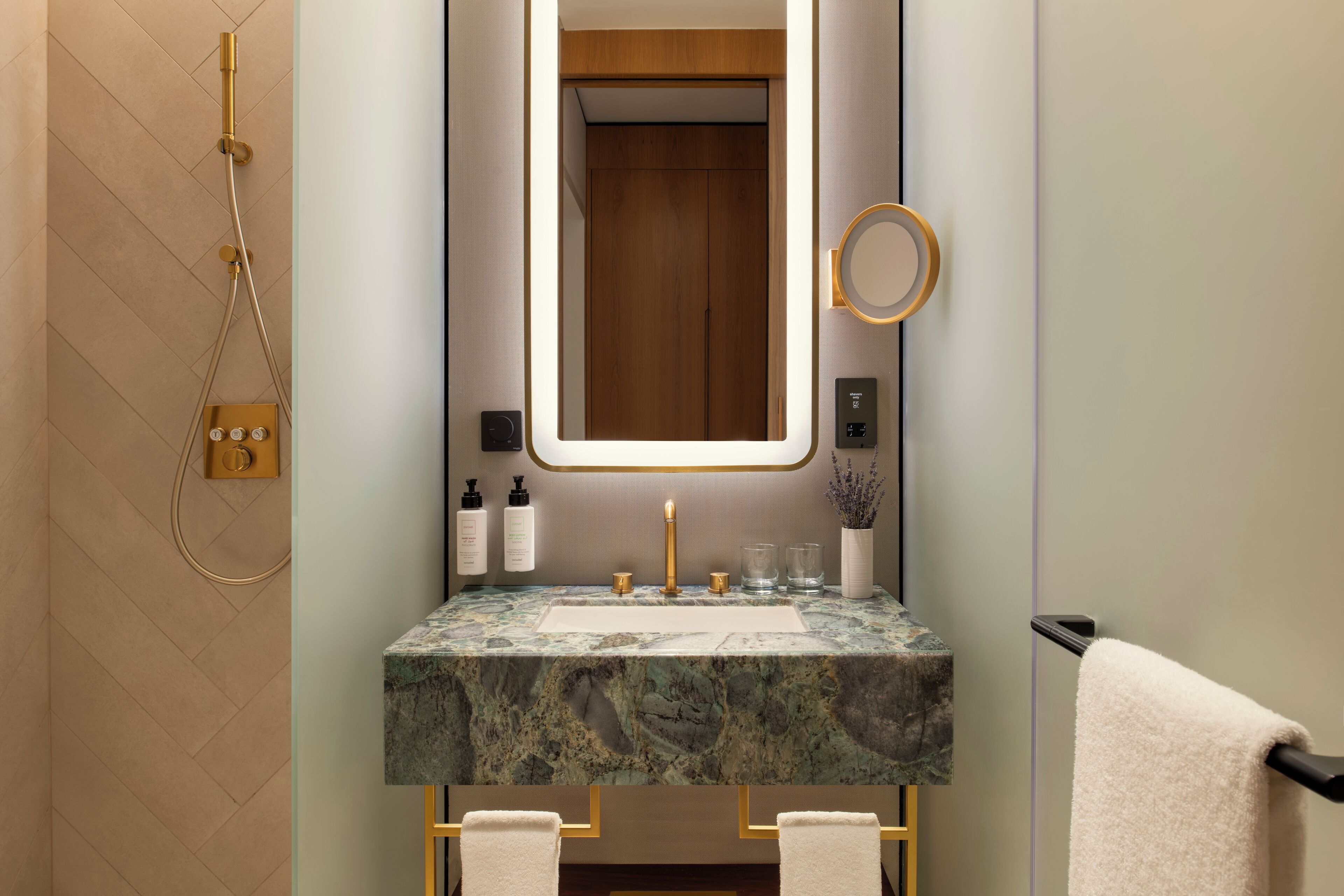 A bathroom with a marble sink, a mirror, a towel rack, and a shower.