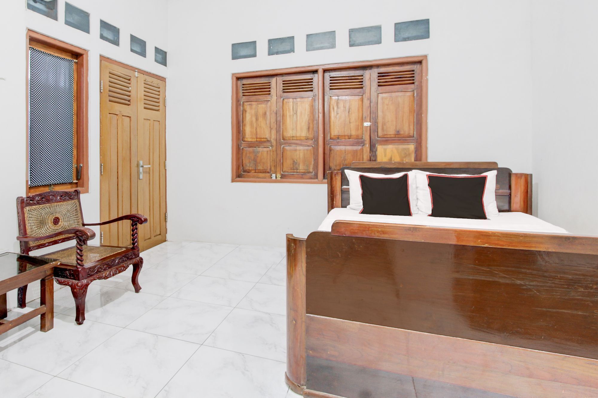 Un dormitorio con una cama y una silla de madera, un armario y una ventana.