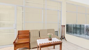 Una habitación con un banco de madera, un sofá color crema y una pequeña mesa con mantel de encaje.