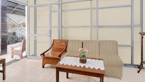 Una habitación con un sofá color beige, una silla de madera y una mesita con mantel de encaje.