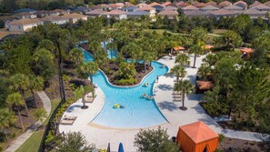 An aerial view of a residential area with a swimming pool surrounded by palm trees and a small pavilion.