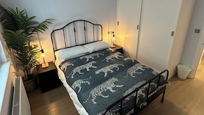 Ein Schlafzimmer mit einem Bett, einem Nachttisch, einer Topfpflanze und einer Heizung.