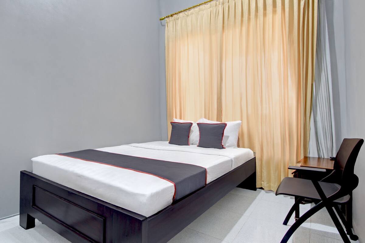 A modern hotel room with a large bed, a desk, and a chair.