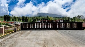 Tagterrasse med udsigt til et bjerg, et hegn og bygninger i baggrunden.
