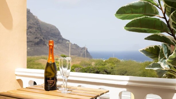 A bottle of Cinzano wine and a glass on a wooden table with a view of a mountainous landscape. - Tenohomes Ocean Light (Buenavista del Norte)