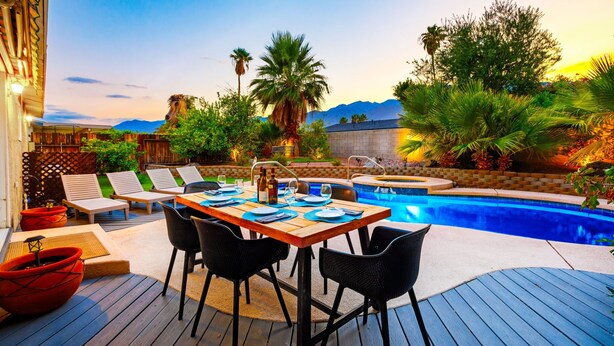 A poolside area with a wooden deck, lounge chairs, a dining table set for two, and a hot tub. - 30% Off September Perfect 4 Families Pool, Jacuzzi (Palm Springs)