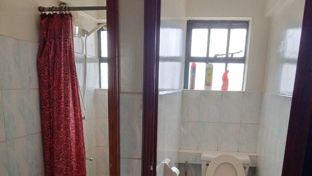 Un baño con ducha, inodoro y ventana.