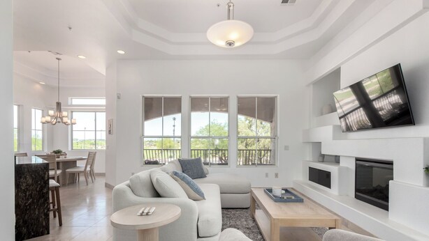 A spacious living room with a fireplace, a dining area, and large windows offering a view of the outdoors. - Scottsdale Escape: Expansive, Stylish 3-Bedroom (Scottsdale)