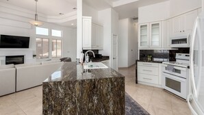 A modern kitchen with white cabinetry, a marble island, and built-in appliances. - Scottsdale Escape: Expansive, Stylish 3-Bedroom (Scottsdale)
