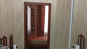 A bedroom with a wooden bed, a desk with a chair, and a wardrobe.