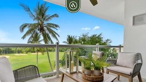 Ein Balkon mit Korbmöbeln, einem Holztisch und einem Blumentopf.