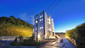A multi-story building with a modern architectural design, featuring a prominent entrance and a staircase leading to the upper levels. - Riverside Chibana (Okinawa)