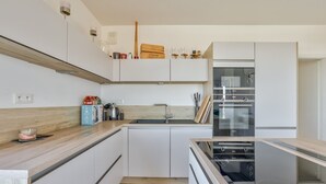 A modern kitchen with white cabinetry, a wooden countertop, a built-in oven, and a sink. - Stunning 1BR Flat with Terrace and private parking (Strasbourg)