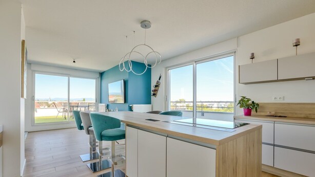 A modern kitchen with a central island, large windows, and a view of the cityscape. - Stunning 1BR Flat with Terrace and private parking (Strasbourg)