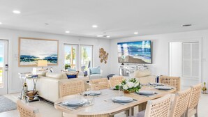 A modern dining area with a round table, white chairs, and a television mounted on the wall.