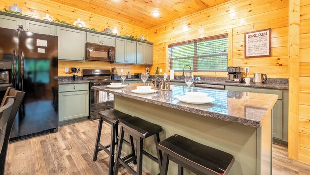 A modern kitchen with wooden walls, a granite countertop, and bar stools.