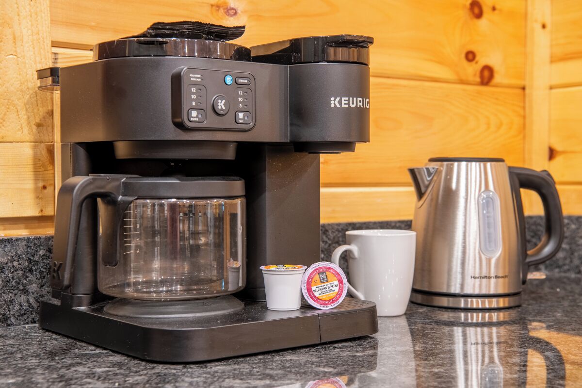 A Keurig coffee maker with a coffee pot, a mug, and a K-cup pod on a granite countertop.