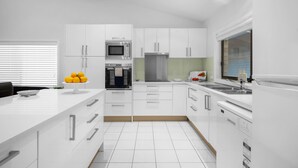 Cocina moderna con muebles blancos, electrodomésticos de acero inoxidable y una isla central.