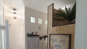 A bathroom with a wooden partition, a framed marine turtle poster, a towel hanging, and a shower area. - Seasonal rental (Lioux)