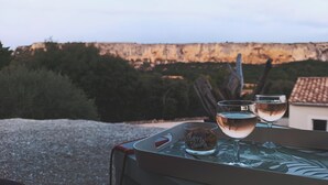 A table with two glasses of wine and a dessert, set against a backdrop of a cliff and trees. - Seasonal rental (Lioux)