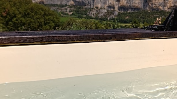 A pool with clear water, a white deck, and a rocky cliff in the background. - Seasonal rental (Lioux)