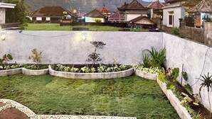 Een woonwijk met huizen, een tuin en een berg op de achtergrond.