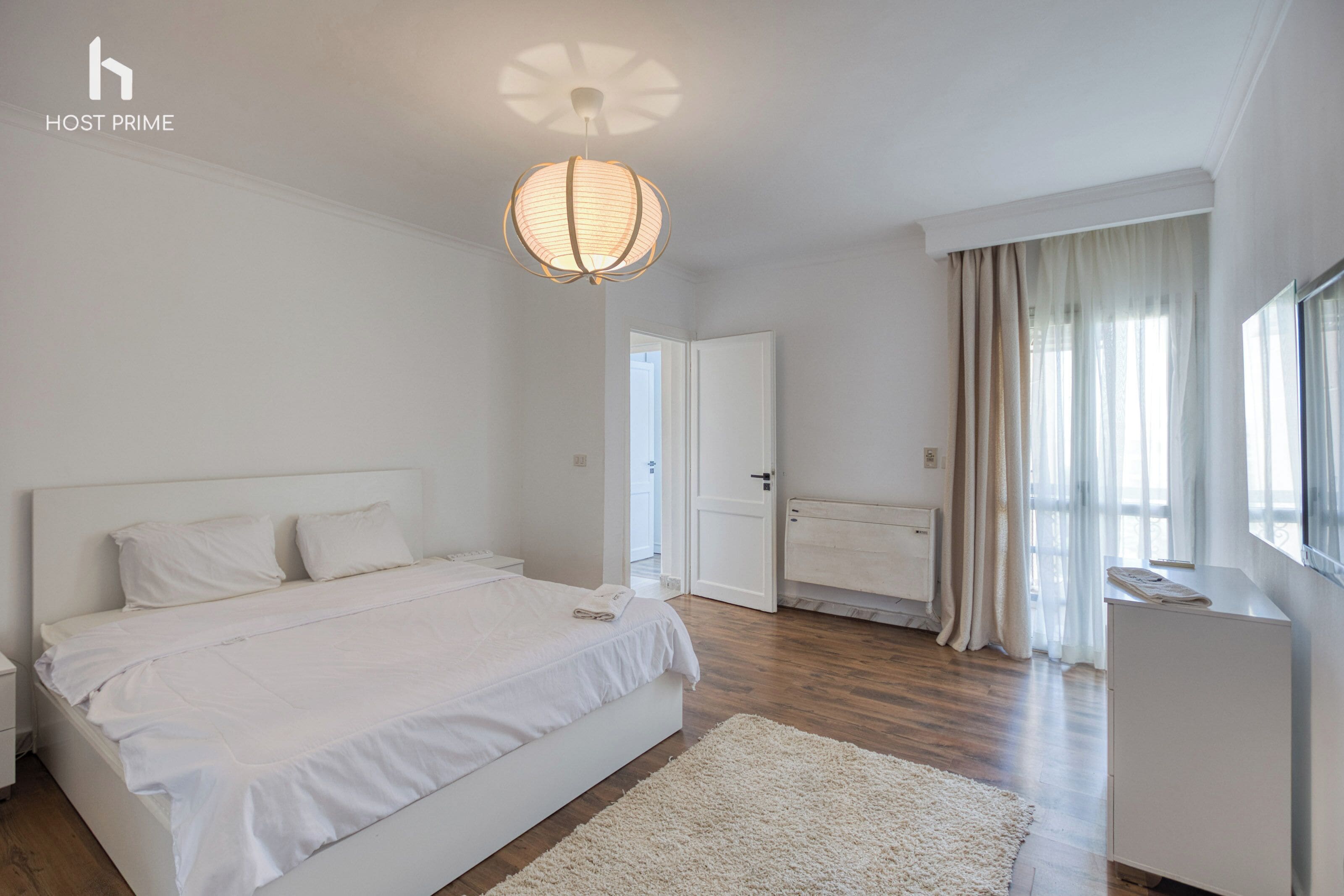 Un dormitorio moderno con una cama grande, una mesita de noche, un tocador y una lámpara en el techo.