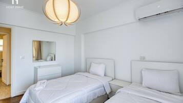 Habitación de hotel con dos camas, una mesita de noche, un espejo y una lámpara colgante.