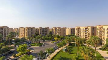 Um complexo residencial com vários edifícios de apartamentos, uma rotatória central e áreas verdes ao redor.