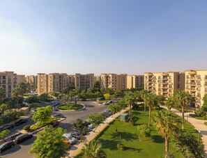 A residential complex with multiple apartment buildings, a central roundabout, and surrounding greenery. - Grand Stay Apartment in Rehab City (New Cairo)