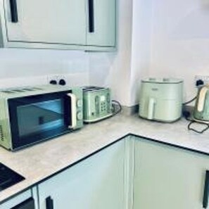 A kitchen with a microwave, toaster, and coffee maker on the counter. - Dover Castle Luxury Apartments (Kent)