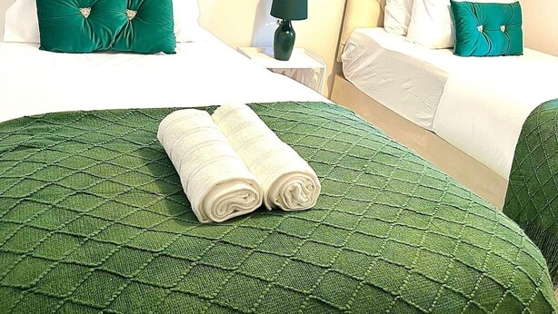 A hotel room with two beds, each with green and white bedding, and a green quilted bedspread. - Port of Dover Luxury Apartments (Kent)