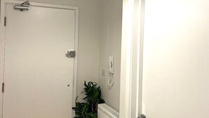 A hallway with a white door, a radiator, and a potted plant. - Port of Dover Luxury Apartments (Kent)