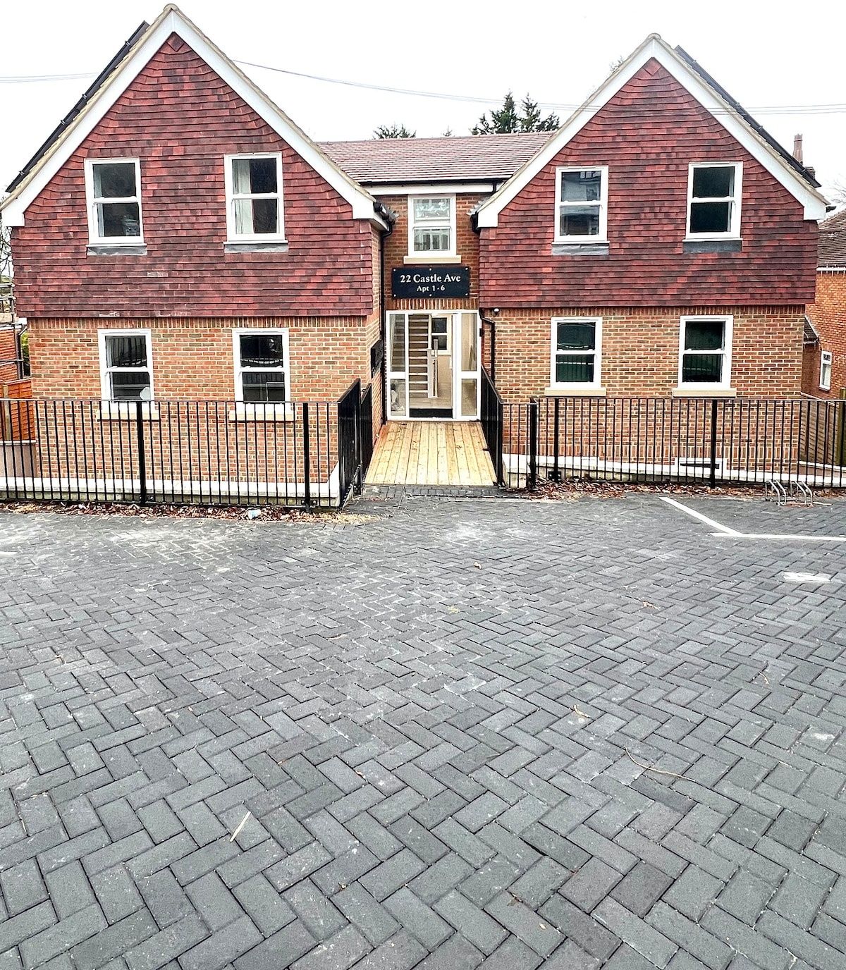 A two-story building with a brick facade, a sign reading "22 Castle Ave Apt 1-6", and a gated entrance.