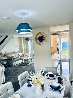 Un salon moderne avec un canapé, une table basse et une table à manger pour quatre personnes.