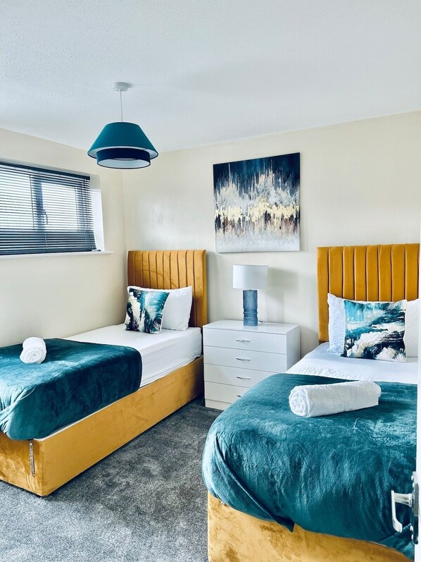 Une chambre d’hôtel avec deux lits, une table de chevet, une lampe et un tableau au mur.